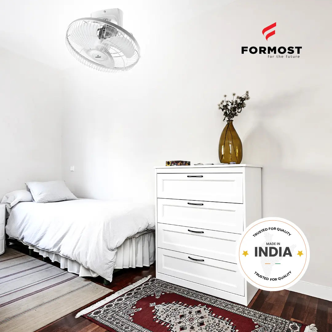Modern bedroom with white bed and dresser, Formost fan, and 'Made in India' badge.